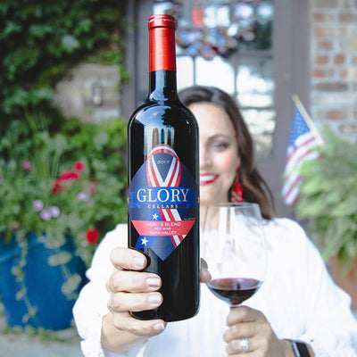 Consultant holding a bottle and filled glass of Glory Cellars 2017 Hero's Blend