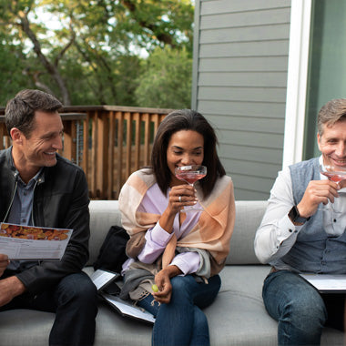 Three friends enjoying wine at home on an outdoor patio.