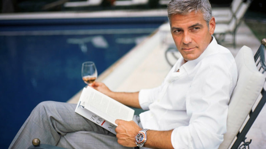 George Clooney reading while holding wine