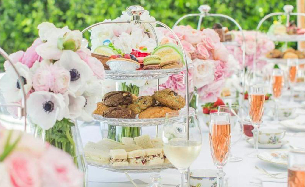 English themed outdoor tea party decorated with flowers, cookies and wine.