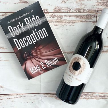 A bottle of Infinite Widsom 2020 Shiraz next to a paperback copy of "Dark Ride Deception"